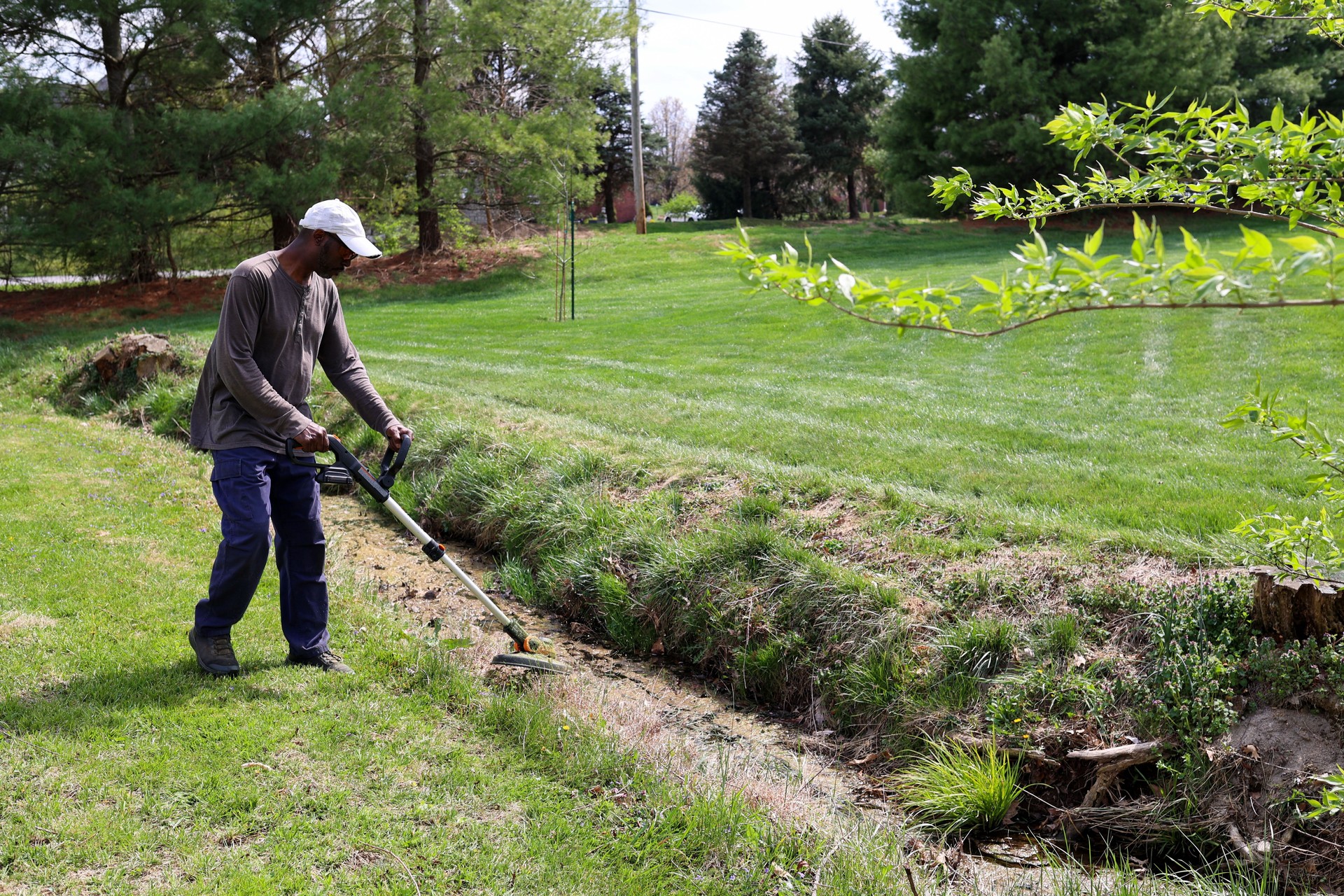A portrait of a black man weeding grass with a trimmer