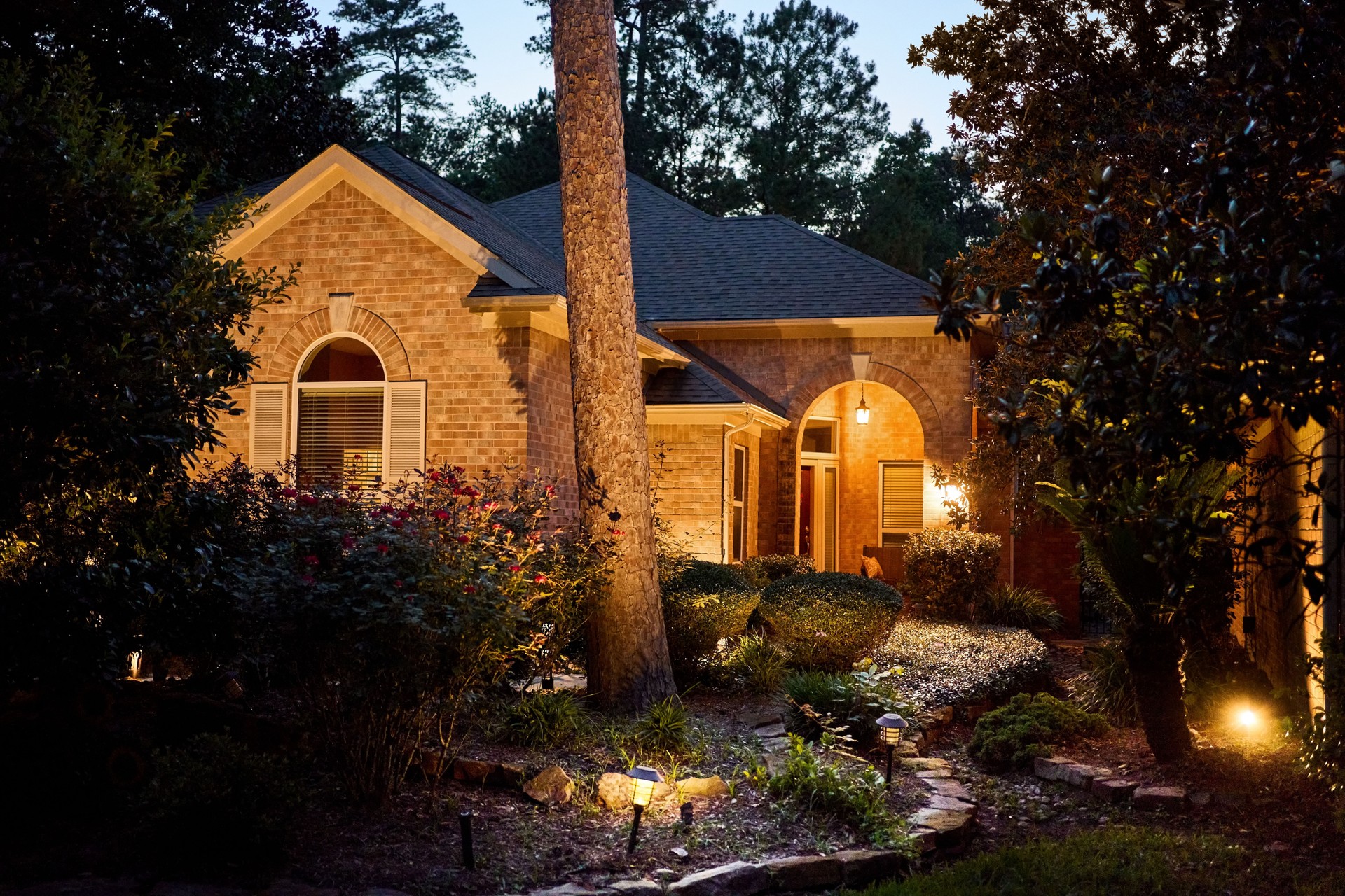 Elegant stone and brick home with vibrant garden at night - Nighttime version